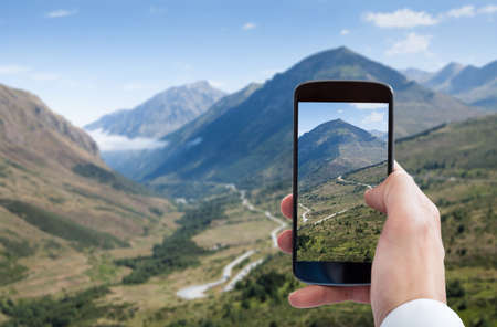 Close-up Of Person Hand Photographing Landscape With Mobile Phoneの写真素材