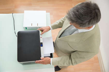 High Angle View Of A Businessman Using Photocopy Machine In Office