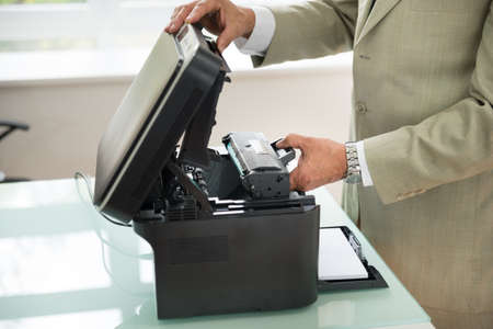 Close-up Of Businessman Fixing Cartridge In Photocopy Machine In Office