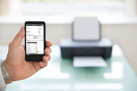 Close-up Of A Businessman Using Cellphone For Printing Invoice. Photographer owns copyright for images on screenの写真素材