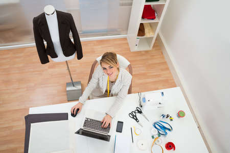 High Angle View Of Female Fashion Designer Using Laptop In Studio