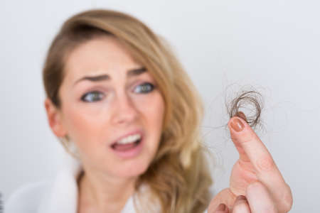 Close-up Of Worried Woman Holding Loss Hair