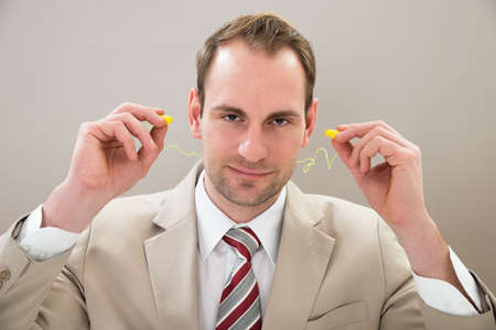 Portrait Of Businessman With Yellow Earplugs In Office
