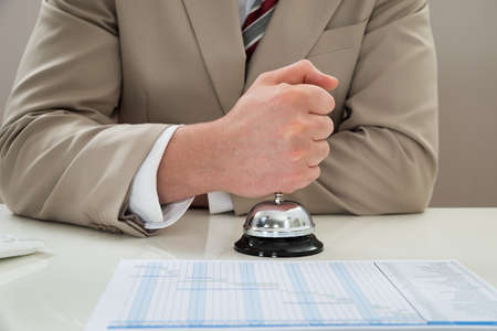 Close-up Of Businessman Ringing Service Bell At Deskの写真素材