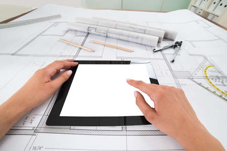Draftsman Hands With Blank Digital Tablet Over Blueprint In Office. Blueprints were created by photographerの写真素材