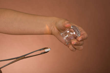 Close-up Of Person's Hand Holding Lit Camphor With Tong And Cupの写真素材
