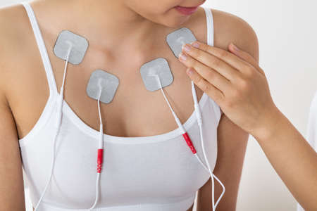 Close-up Of A Therapist Placing Electrodes On Woman's Chestの写真素材