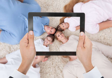 Close-up Of Person Hand Photographing Family Lying On Beachの写真素材