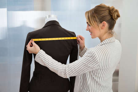 Portrait Of Fashion Designer Measuring Suit With Measuring Tapeの写真素材