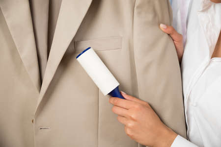 Close-up Of Woman Cleaning Coat With Adhesive Rollerの写真素材