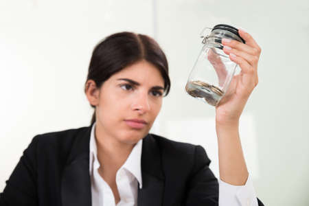 Portrait Young Businesswoman Holding Jar With Coinsの写真素材