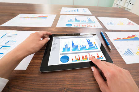 Close-up Of Businessperson Hands Analyzing Graph On Digital Tablet At Desk. Photographer owns...