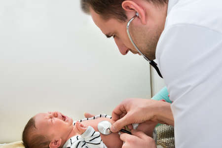 Close-up Of Male Doctor Examining Crying Babyの写真素材