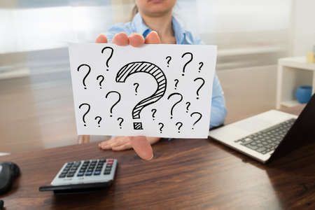 Businesswoman Showing Question Mark Sign On Placard In Officeの写真素材