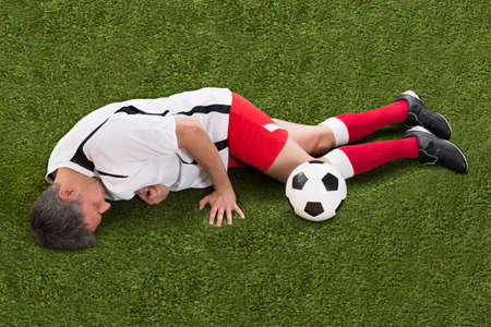 High Angle View Of Injured Soccer Player Lying On Grassの写真素材