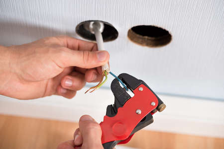 Closeup Of Electrician Hands Stripping Electrical Wires For Wall Socket