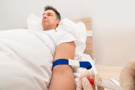 Doctor Taking Blood Samples Of Patient With The Help Of Injectionの写真素材