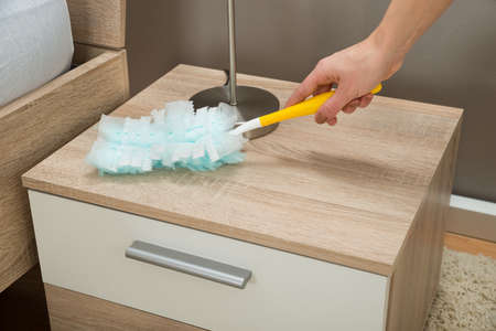 Close-up Of Hand Removing Dust From Nightstand With Duster Featherの写真素材