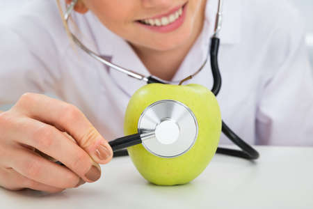 Female Dietician Examining Green Apple With Stethoscopeの写真素材