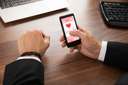 Businessman With Smart Wristband And Cellphone Showing Heart Rateの写真素材