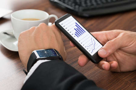 Close-up Of A Businessman Analyzing Graph On Cellphone