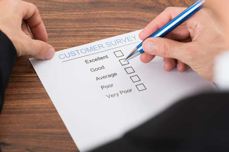 Close-up Of Person Hand Filling Customer Survey Form With Penの写真素材