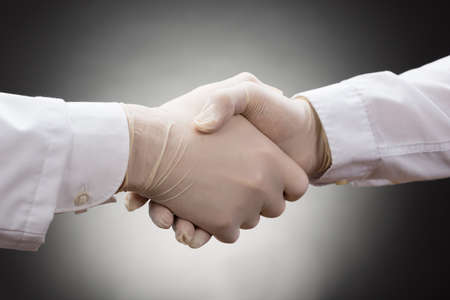 Close-up Of Two Doctor's With Glove Shaking Handの写真素材