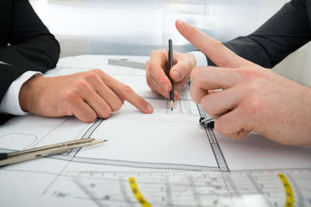 Close-up Of Two Architects Planning Project On Blueprintの写真素材