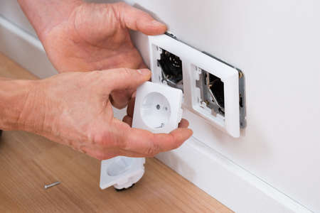 Close-up Of A Technician Adjusting Socket On Wall