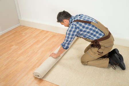 Male Worker Unrolling Carpet On Floor At Homeの写真素材