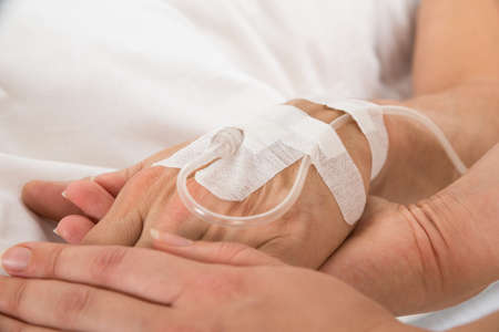 Close-up Of Doctor's Hand With Iv Drip Inserted In Patient's Handの写真素材