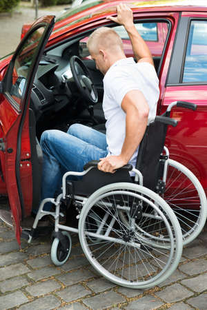 Handicapped Man Sitting On Wheelchair Boarding In His Carの写真素材