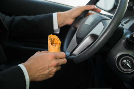 Close-up Of A Male Holding Snack While Driving In His Car
