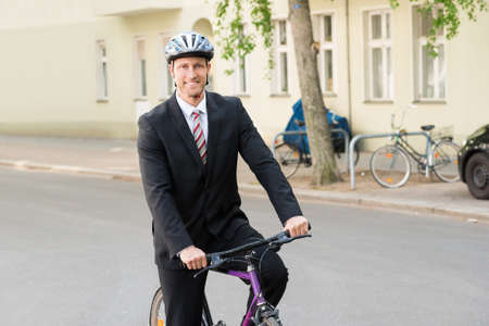 Portrait Of A Happy Businessman Riding On His Bicycleの写真素材