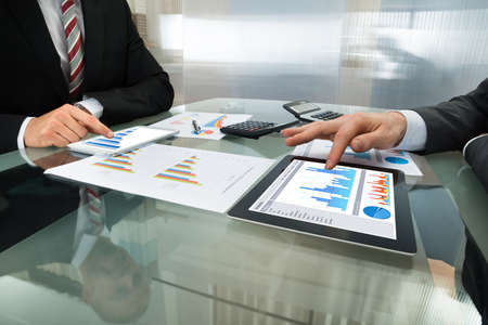 Close-up Of Two Businessman Analyzing Graph On Digital Tablet Close-up Of Two Businessman Analyzing Graph On Digital Tablet
