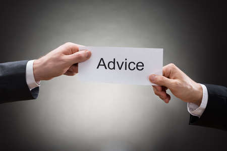 Close-up Of Two Businessman's Hand Holding Paper With Advice Word On Itの写真素材