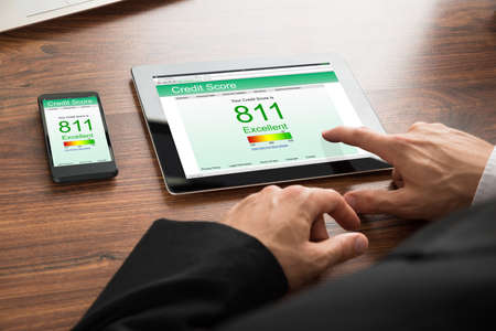 Close-up Of A Businessman Checking Credit Score Online On Digital Tablet And Cellphoneの写真素材