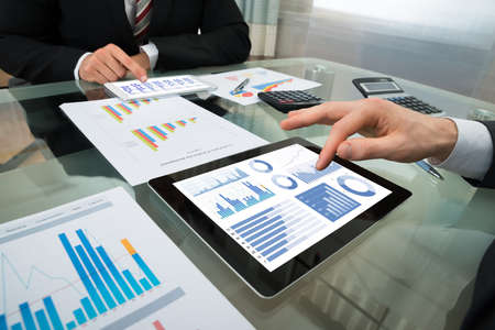 Close-up Of Two Businessman Analyzing Graph On Digital Tablet Close-up Of Two Businessman Analyzing Graph On Digital Tablet
