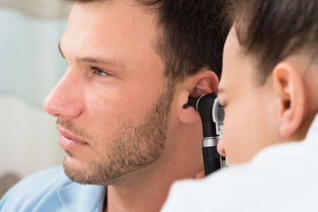 Physician Looking Into Male Patient's Ear With An Instrumentの写真素材