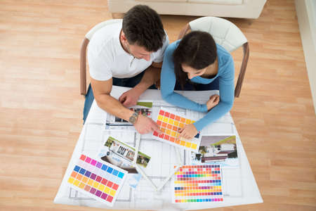 High Angle View Of Young Couple Choosing Color From Swatch