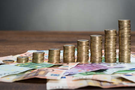 Close-up Of A Stacked Coins Arranged On Euro Banknotesの写真素材