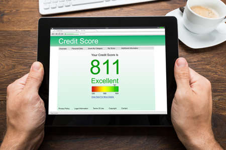 Close-up Of Person Hands With Digital Tablet Showing Credit Score At Deskの写真素材