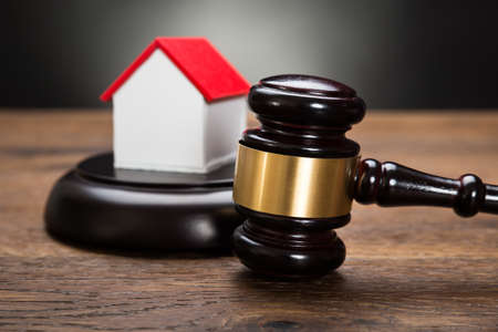 Close-up Of House Model With Gavel On Wooden Tableの写真素材