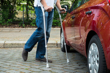 Close-up Of A Disabled Man With Crutches Walking Near Careの写真素材