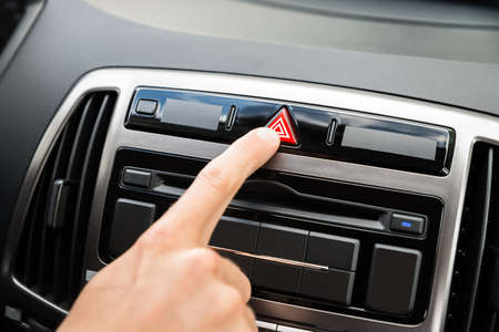 Close-up Of Man's Hand Pressing Emergency Button In Car