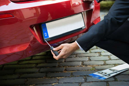 Man Placing New Empty White Number Plate On His Red Carの写真素材