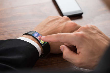 Close-up Of Businessman's Hand Wearing Smartwatch Pressing Call Buttonの写真素材