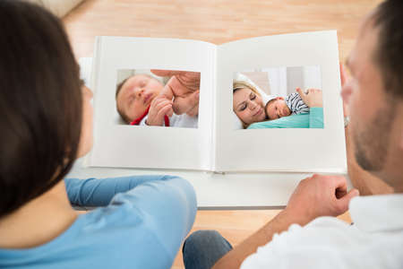 Close-up Of Couple Looking At Baby's Photo Album