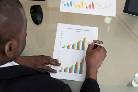 Young African Businessman Working With Graph At Desk In Officeの写真素材
