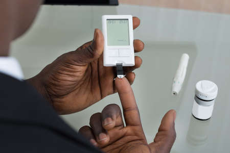 Close-up Of Patient Hands Measuring Glucose Level Blood Test With Glucometerの写真素材